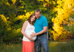 Photo of an expecting mother with her partner who is touching her pregnant belly.