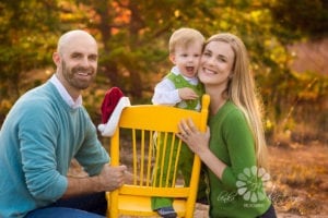 Family of three with a small boy standing on a yellow chair.