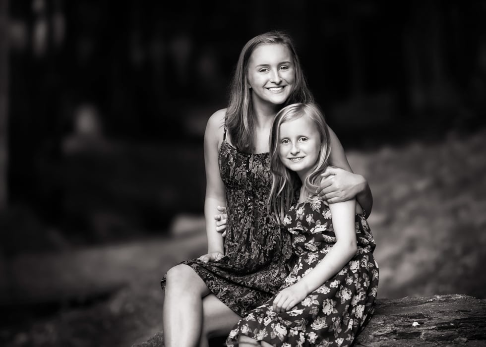 A black and white photo of two sisters sitting on a rock s