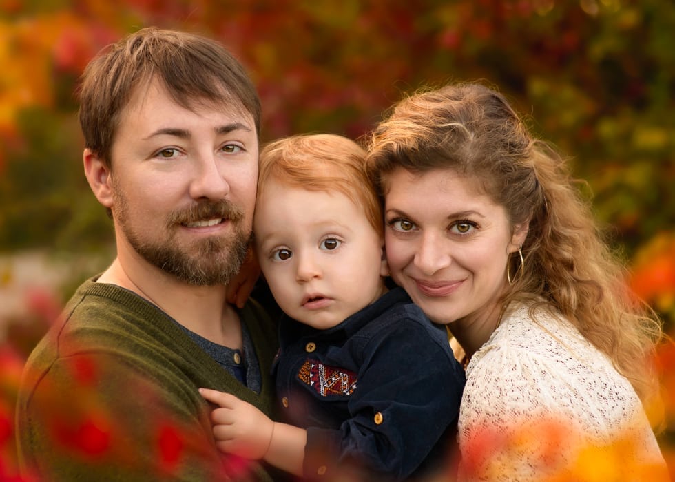 A closeup of a family of three in fall setting.