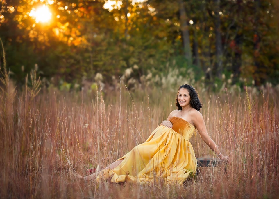 A professinal photo of a pregnant woman in a yellow long dress.