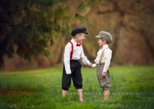 A professional photo of two cute little boys holding their hands and looking at each other.