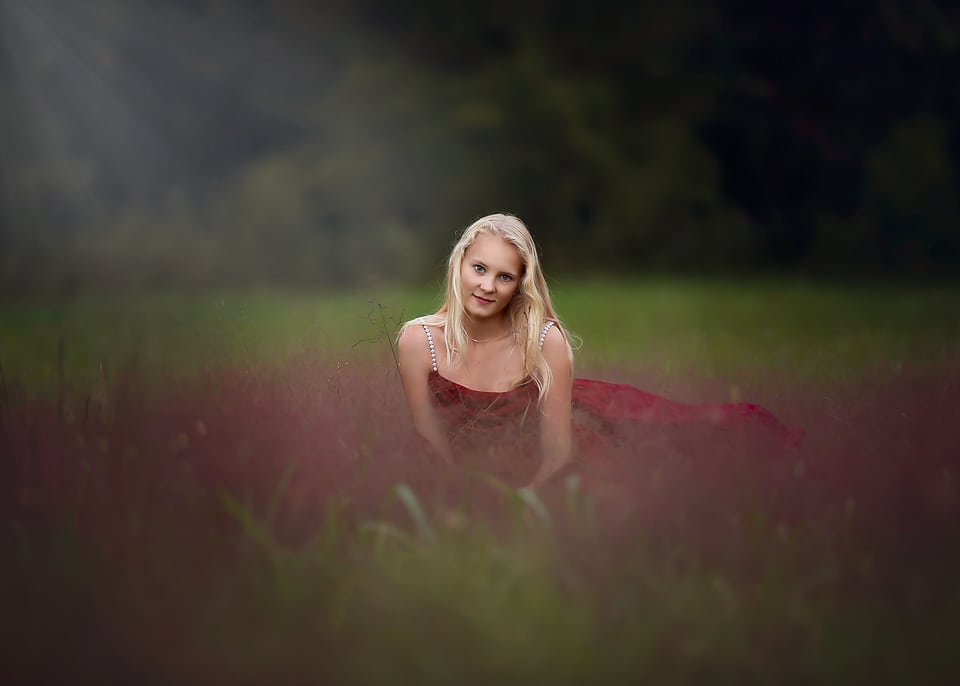 A prefessional image of a young gril sitting in a field of grass.