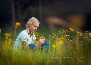 A beautiful image of a girl sitting in a grass full of yellow flower.