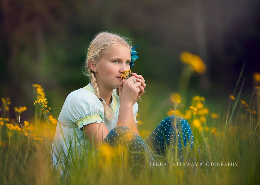 An image of a pre-teen girl sitting down and smelling yellow flower. Yellow flowers are all around her.