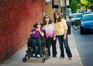 A professional image of a family of three. One child is on a wheelchair. Photo is taken downtown Asheville.