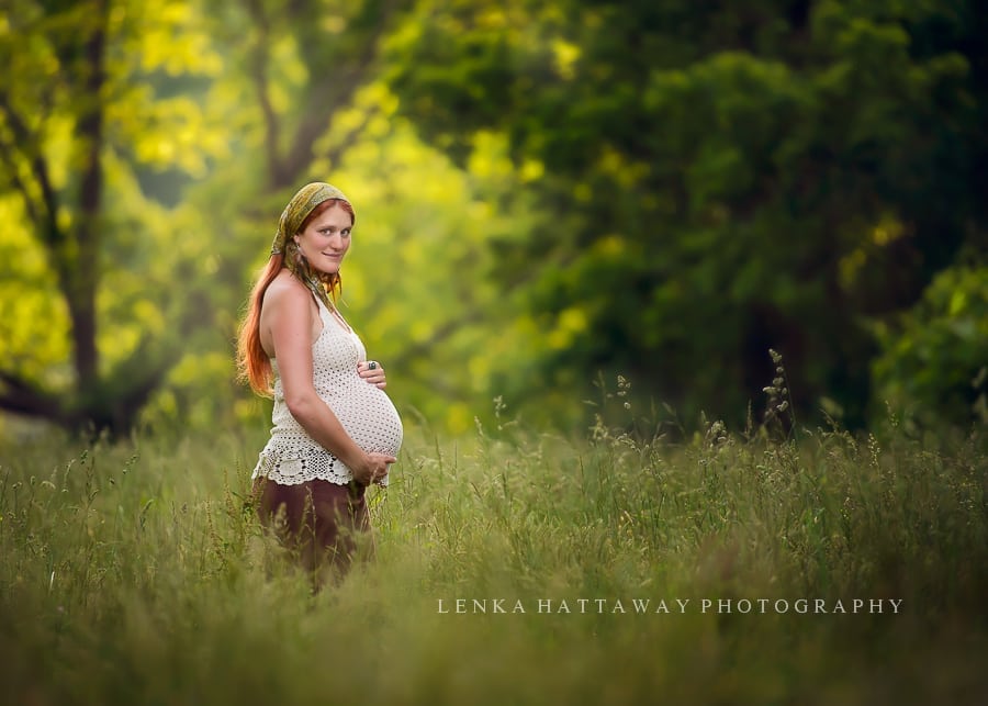 A professional image of a pregnant mom standing in a tall grass. Photo taken in Asheville.