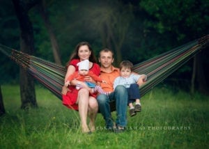 A photo of a family sitting in a hammock.