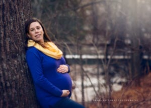 Pregnancy photo of a mom-to-be leaning against a tree.