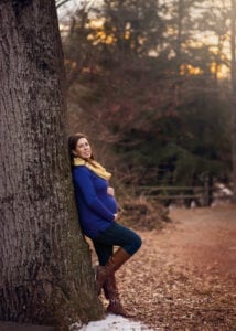 A pregnant woman leaning against the tree.