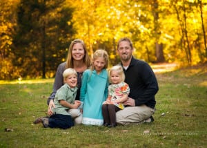 A beutiful photo of a family with fall colors all around.
