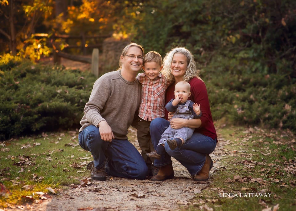 A sweet photo of a family with bautiful fall colors in the background.
