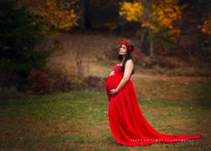 A maternity photo of a beautiful woman in a red gown.