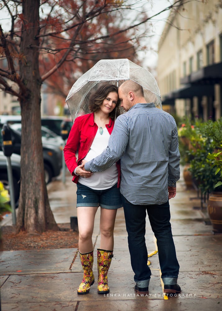 Couple holding an umbrella duing an urban maternity photo session.
