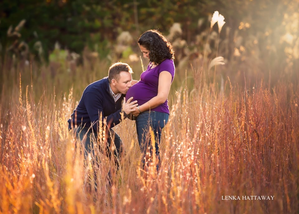 An awesome maternity photo. Partner is kissing woman's belly. Beautiful natural light.