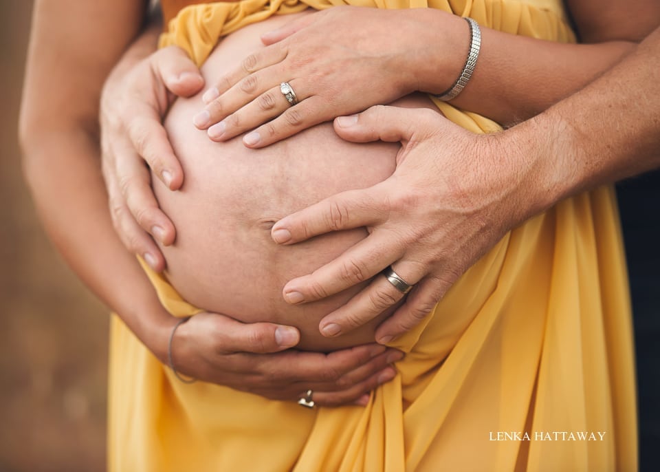 Natural light image of hands on pregnant belly.