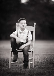 Black and white portrait of a boy sitting on a chair.