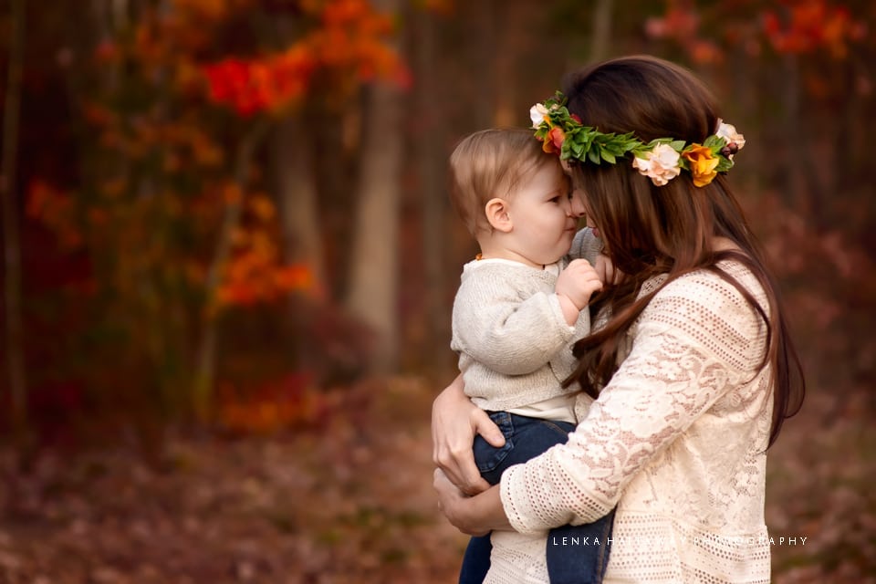 A mother and a baby touching noses. Image has beautiful fall colors.