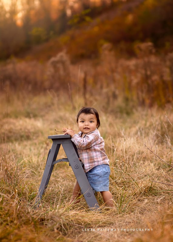 Baby standing next to a small ladder.