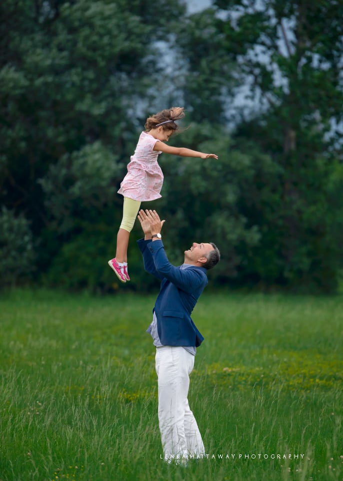 Father throwing his child, his girl, up in the air.