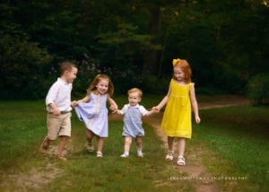 Four siblings walking together holding hands.