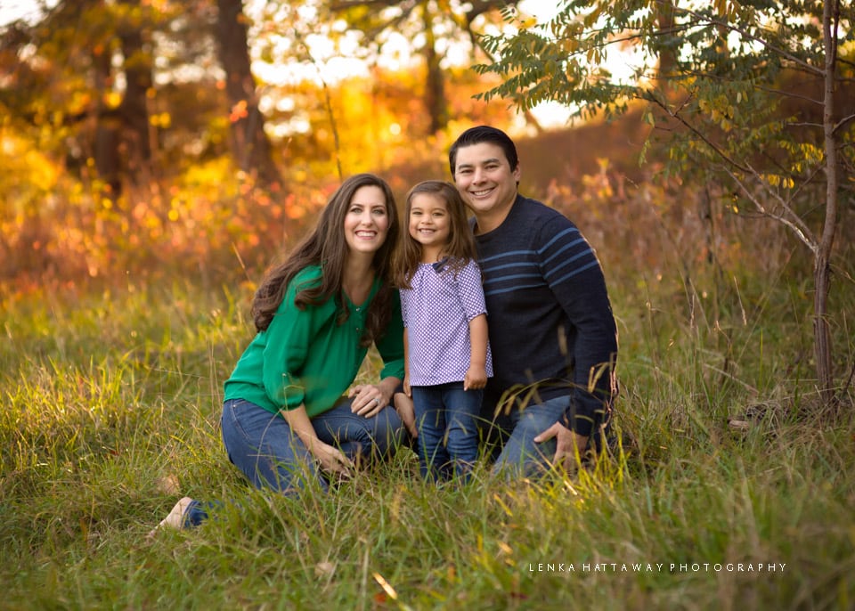 A family of three close together surrounded by beautiful colors.