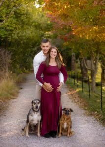 Pregnancy photo fo a couple with their two dogs.