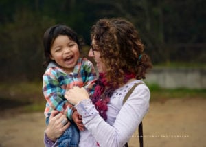 Photoo of a giggling boy aith his mom.