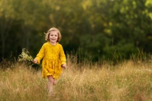Child photo of a girl running and holding flowers.