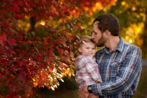Fall photo of dad kissing his child.