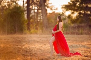 Maternity shot of a mom-to-be in long red gown.