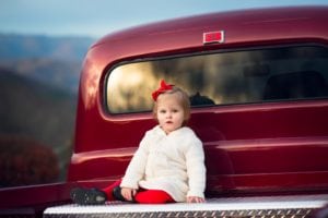 Sweet baby girl in teh back of a red Ford truck.