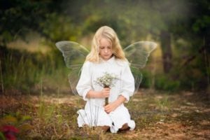 Child photo of a girl with angel wings holding flowers.