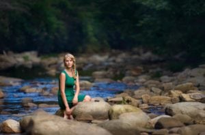 Photo of a teen girl sitting on river boulders in Western North Carolina.