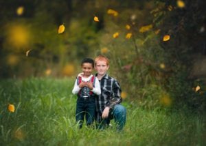Two brothers in a meadow and fall leaves falling.