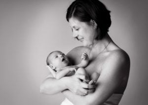 Black and white image of a newborn baby being held by his mom.