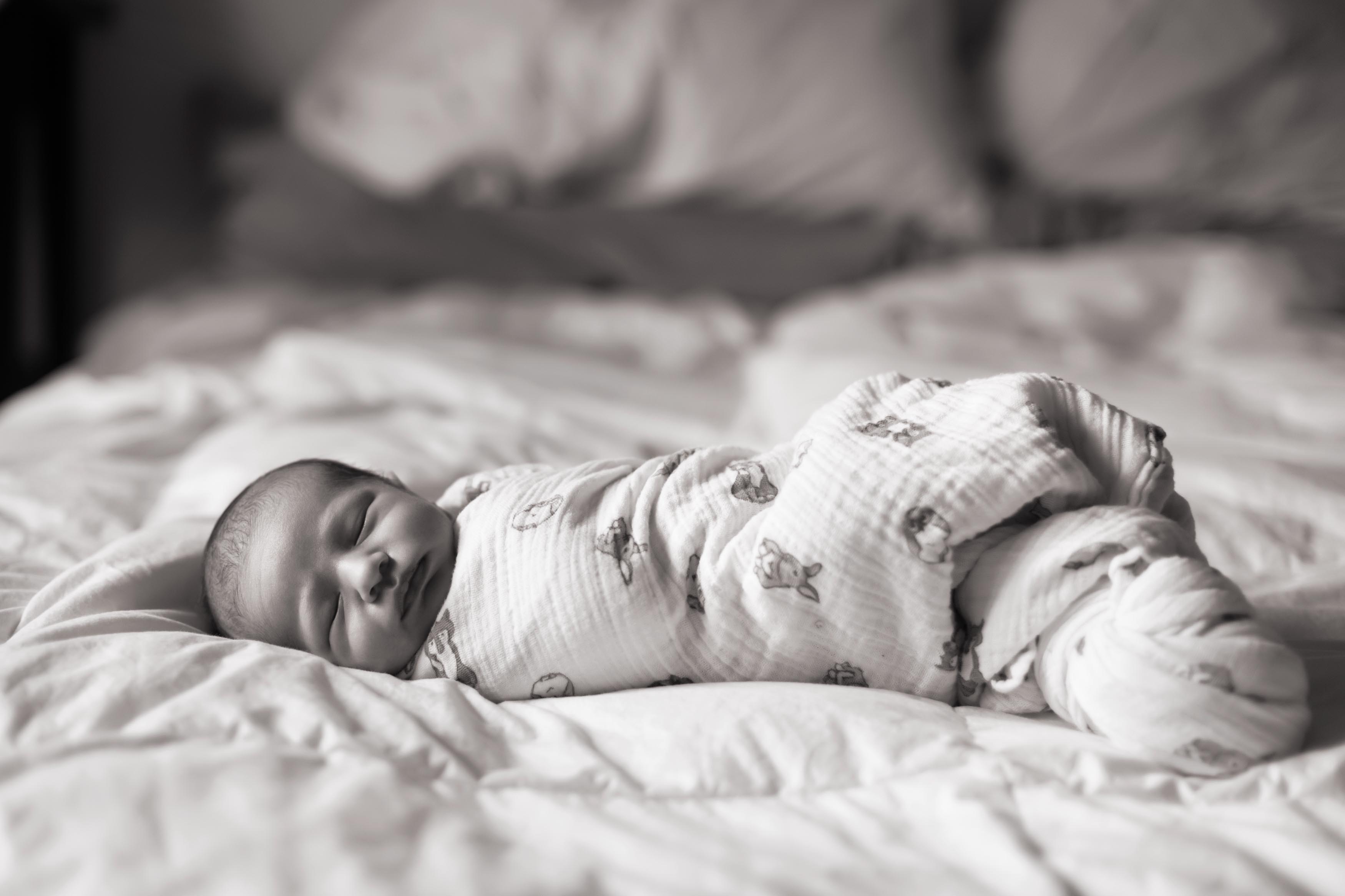 Black and white newborn photo on a bed.