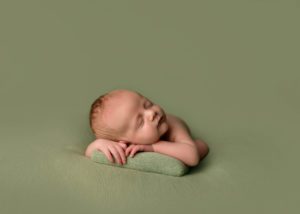 Newborn baby resting on a pillow.