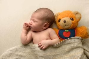 Sleeping newborn with a teddy bear.