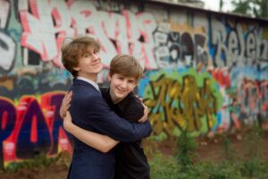 Two brothers hugging during a senior photo session by a graffiti wall.
