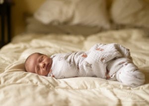 Photo of newborn baby sleeping on a bed by Asheville newborn photographer.