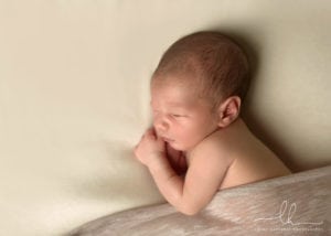 Newborn photo of a baby sleeping on his side.