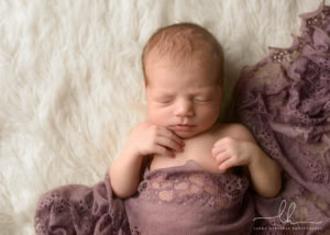 Adorable newborn baby girl wrapped in a scarf.