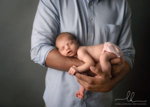 Newborn photography of a baby girl in her dad's arms.