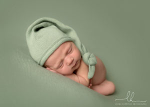 Newborn sleeping in a green cap