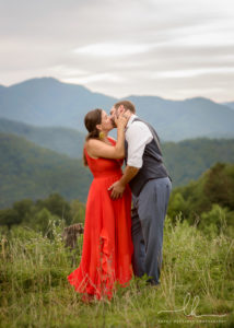Expecting couple kissing with mountains in the background.