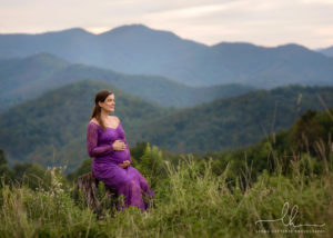Pregnant mom-to-be sitting peacefully, mountains behind her.