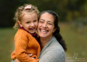 Mom and her daughter smiling into the camera during a family portrait session at the Botanical gardens.
