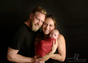 Newborn photography of mom and dad holding their newborn baby girl.
