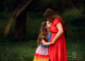 Sweet photo of mom and daughter. Mom kissing daughter on forehead.